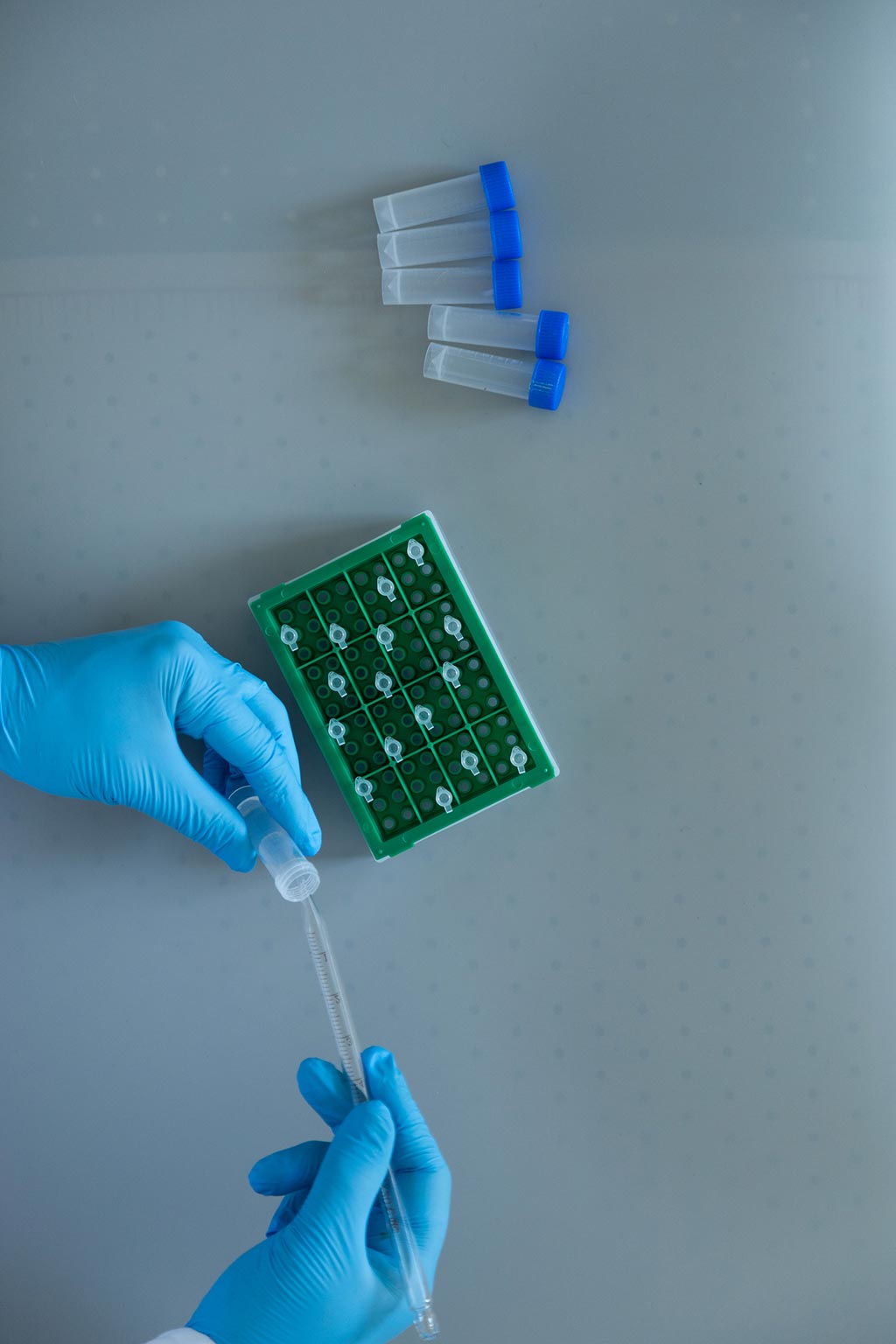 Hands in rubber gloves hold a test tube and testing kit.